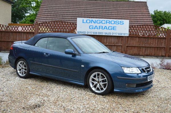 A blue Saab convertible in front of the Longcross Garage sign