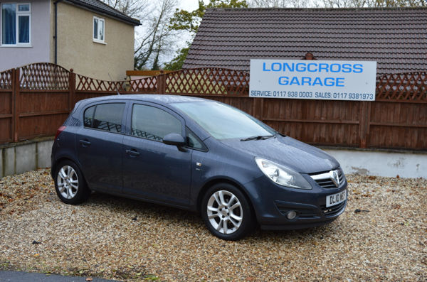 A grey Vauxhall hatchback in front of the Longcross Garage sign