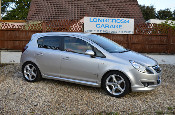A silver Vauxhall hatchback in front of the Longcross Garage sign