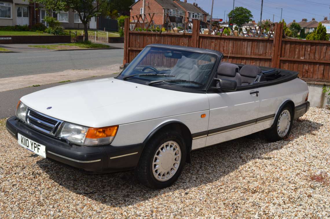 A white 1992 Saab 900 Classic Convertible with the roof down, registration K110 YPF, on the gravel forecourt at Longcross Garage