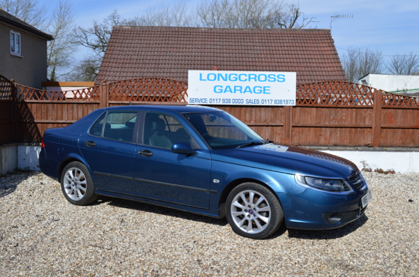 A blue Saab saloon in front of the Longcross Garage sign