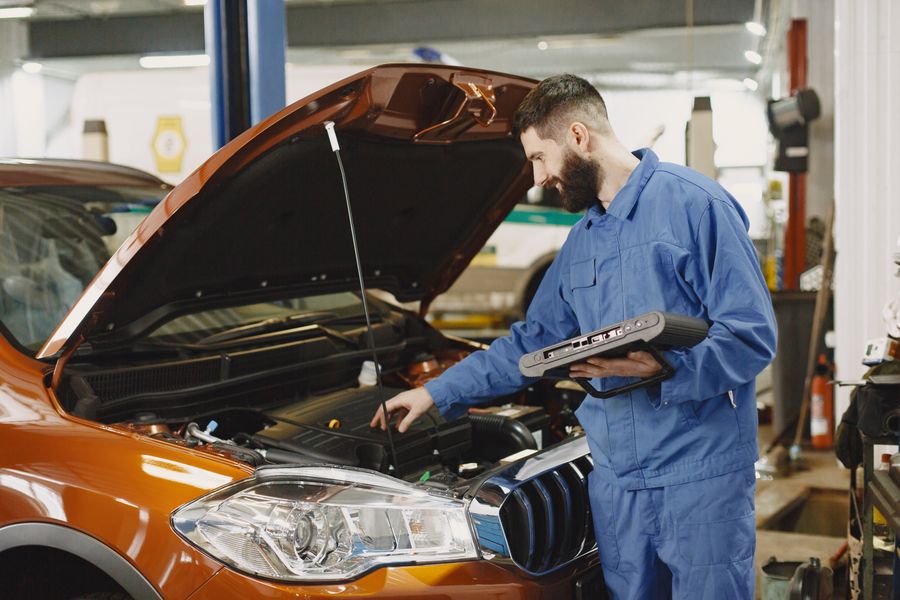 A mechanic working under the bonnet with a diagnostic reader