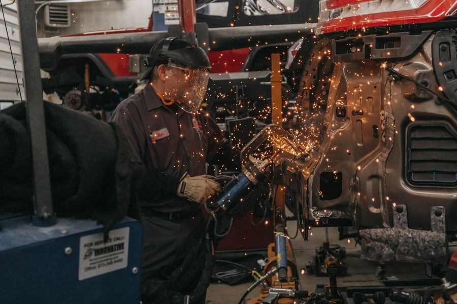 A welder in a mask working on a car body