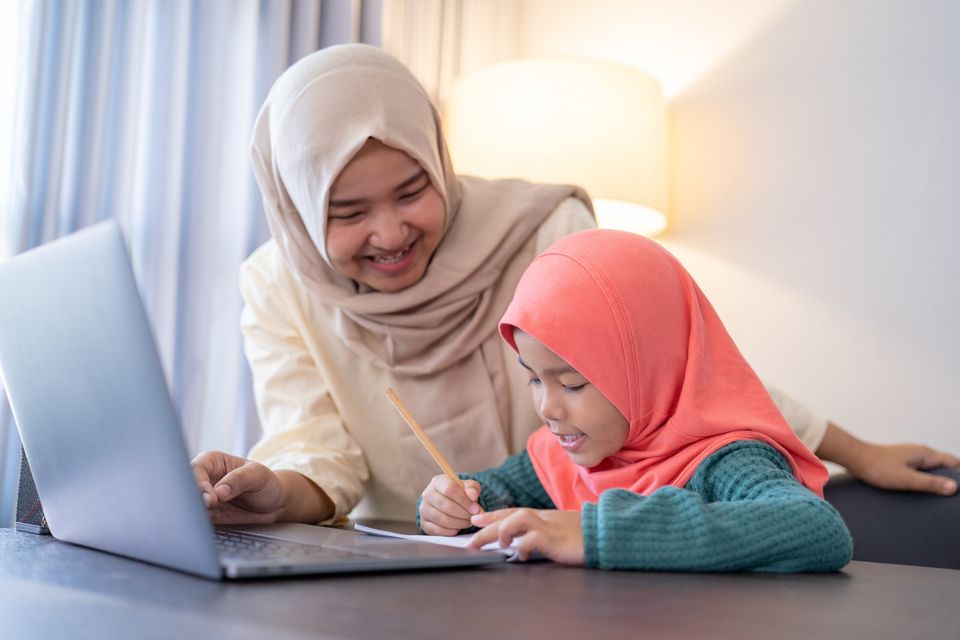 A mother and daughter working together at a laptop