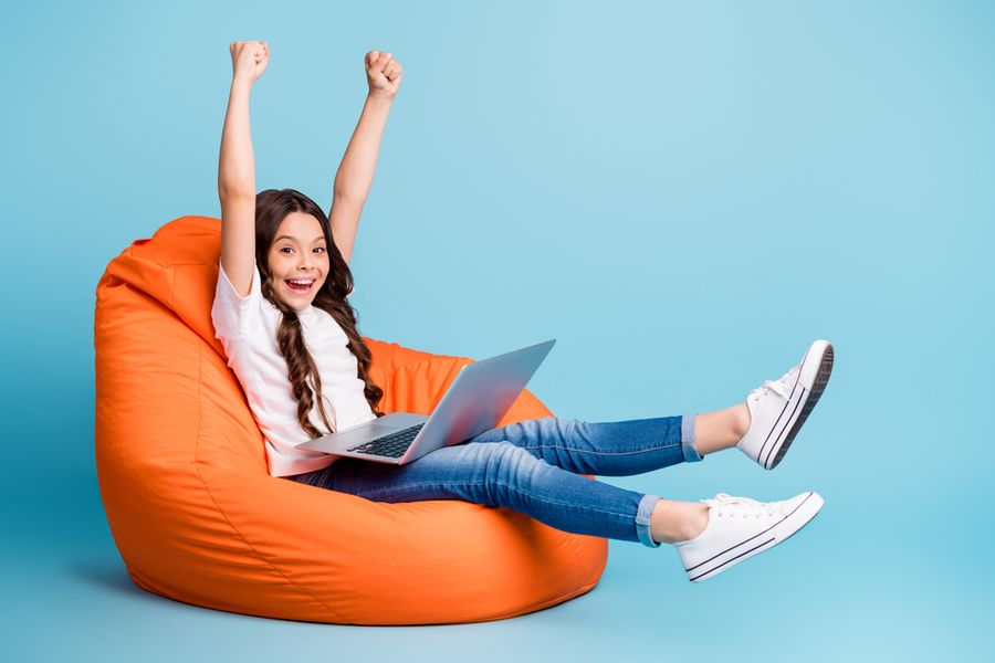 A delighted girl on a beanbag with her laptop