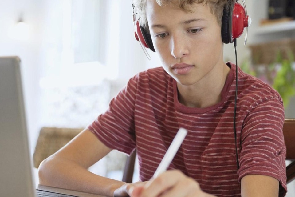 A boy in headphones working at his laptop