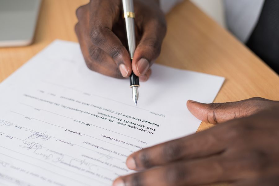 Hands signing a form with a pen