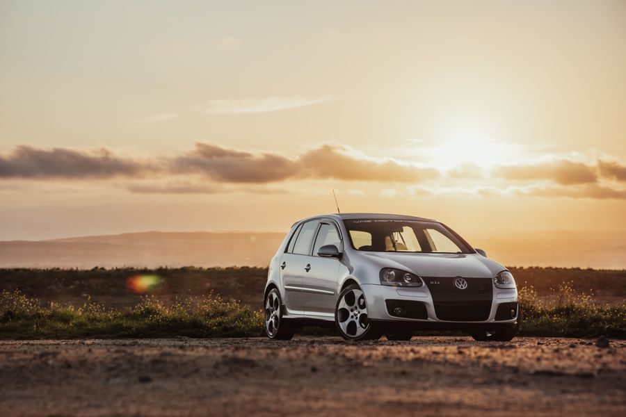 A small hatchback on a country road at sunset