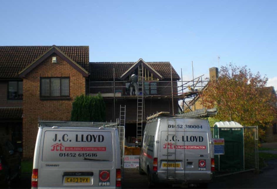 Two J C Lloyd vans outside a house under renovation