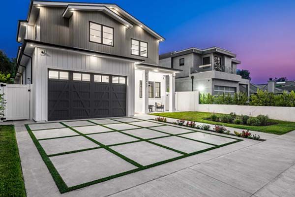 A modern house with a jointed concrete driveway and lawn strips