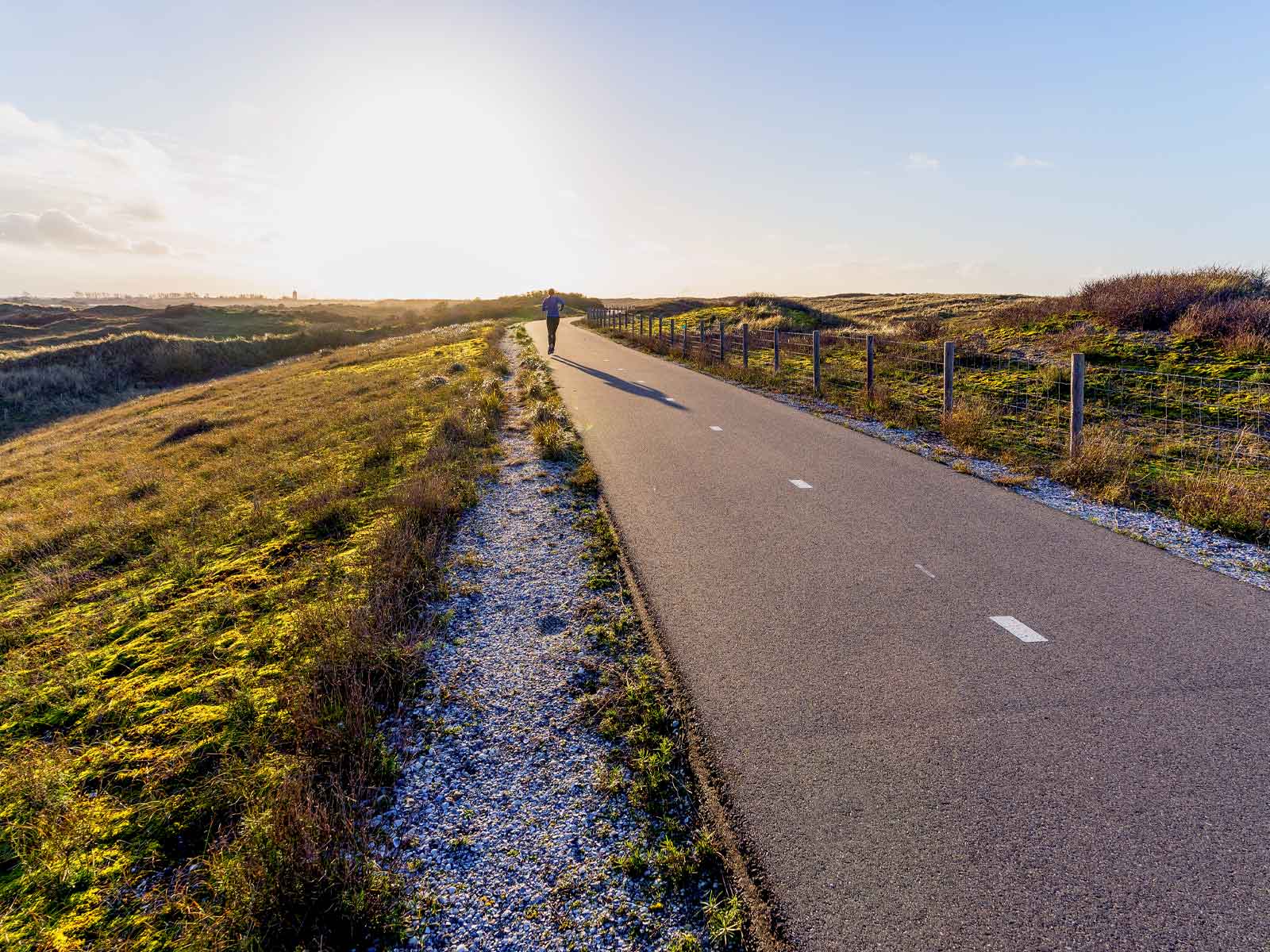 An asphalt footpath running out through open grassland