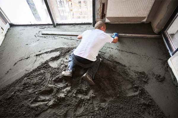 A worker levelling a concrete floor inside a building