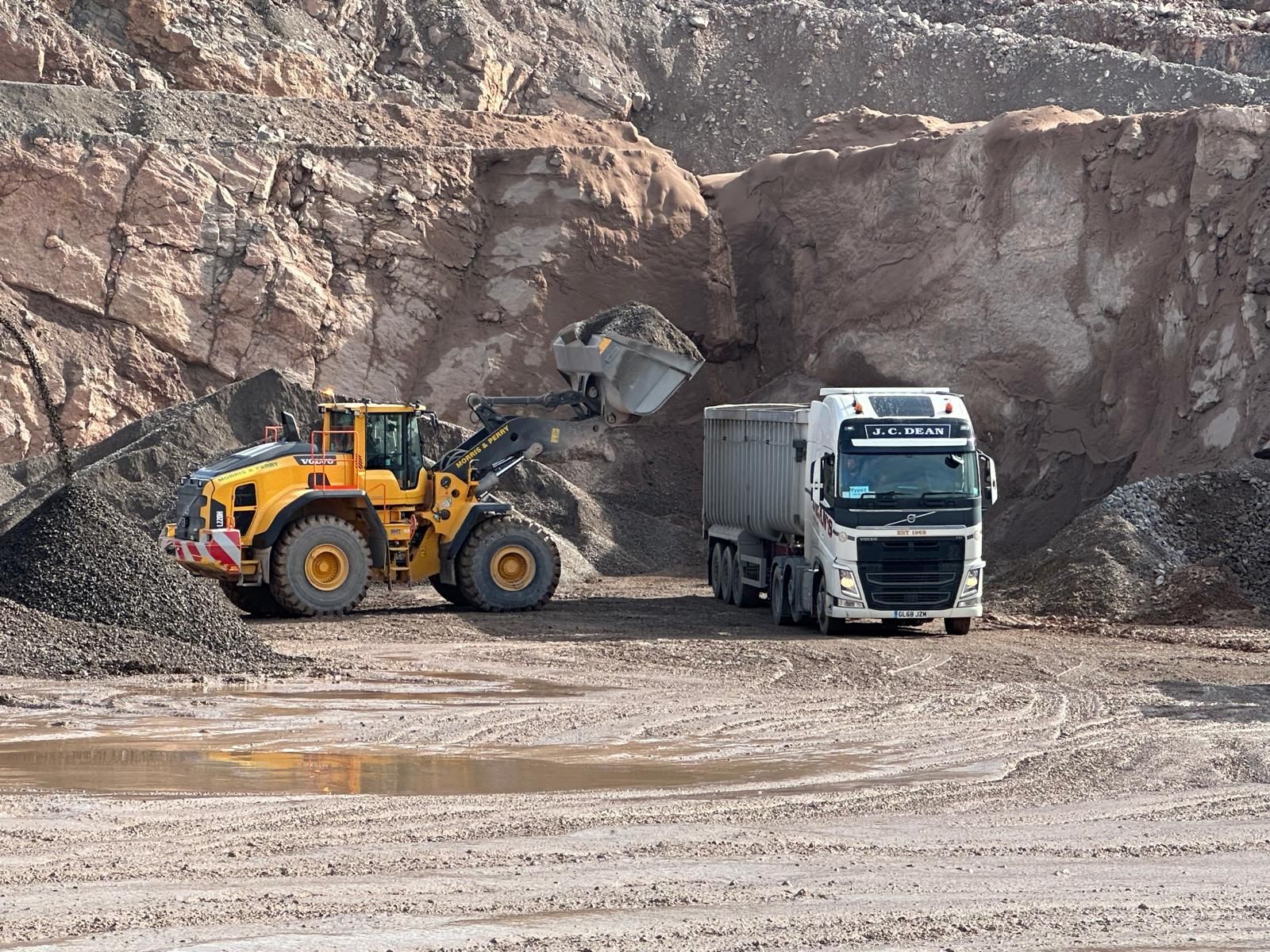 A loading shovel working the face beside a tipper lorry in the quarry