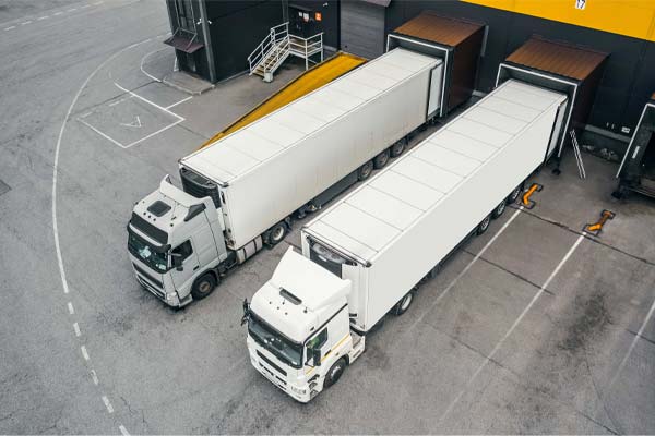 Two lorries backed onto loading bays across a concrete yard