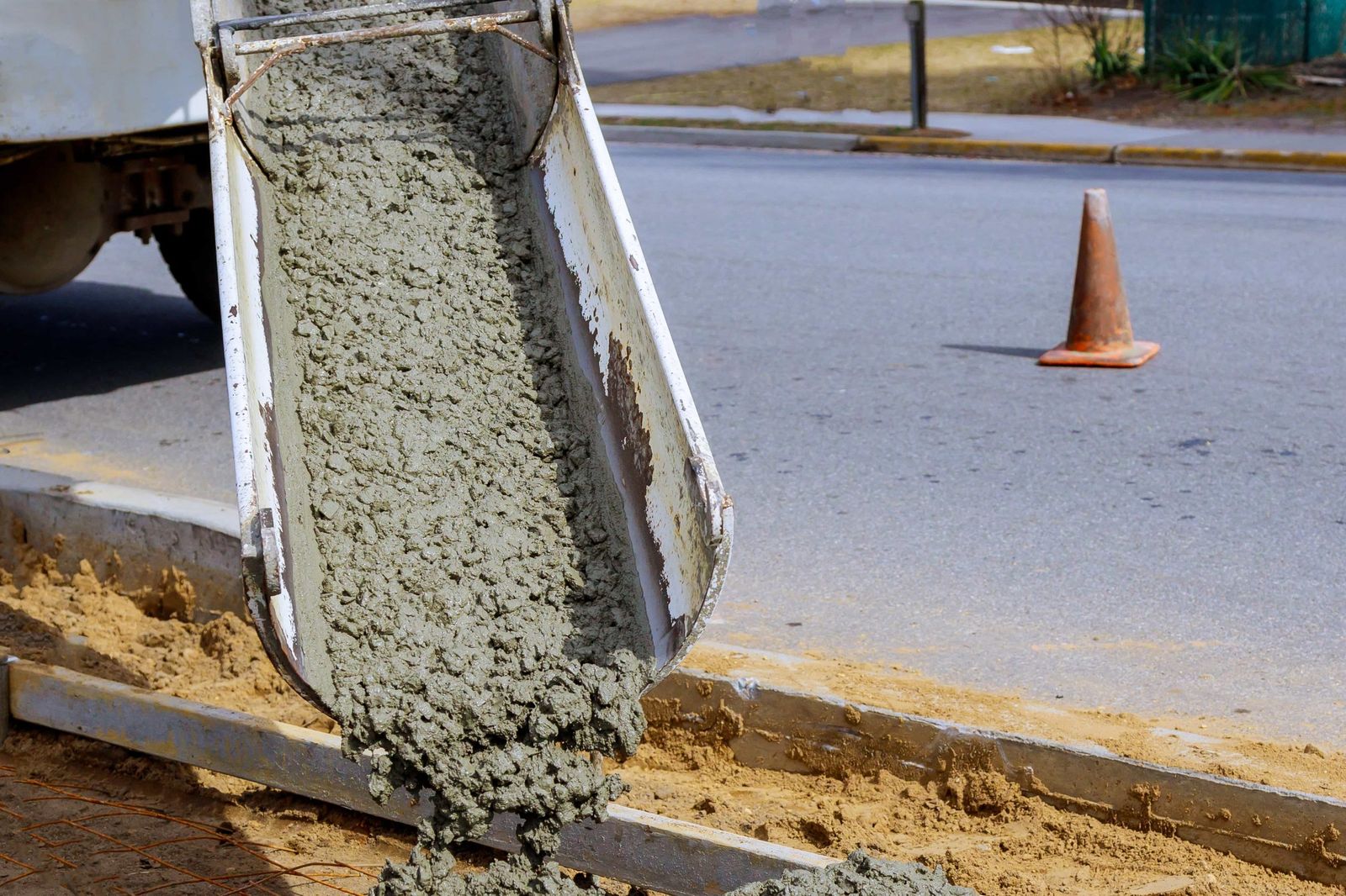 Ready-mixed concrete pouring from a mixer's chute into a kerb-side trench