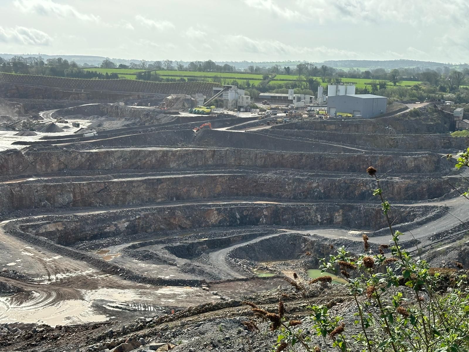 Worked benches stepping down into a limestone quarry under a grey sky
