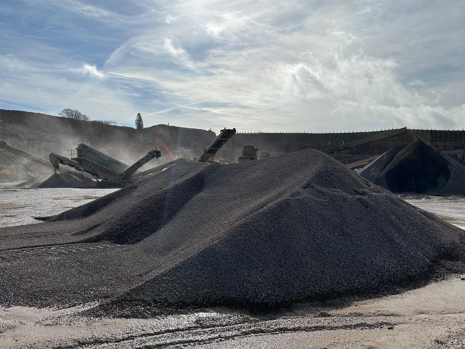 Stockpiles of crushed limestone aggregate under a wide sky at the quarry