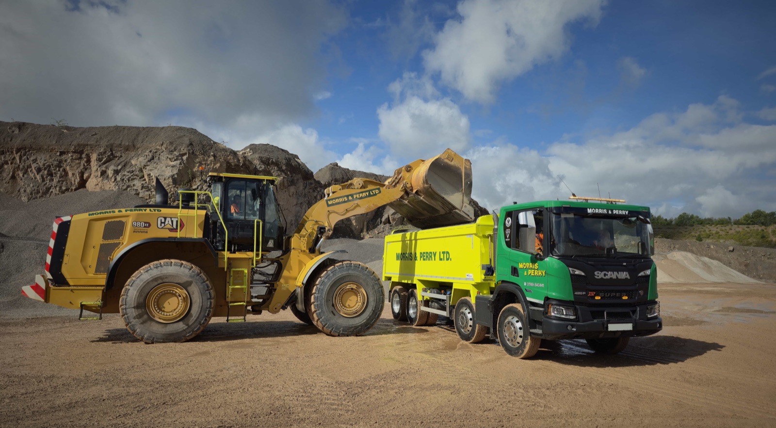 A Morris & Perry loading shovel filling one of our green and yellow tipper lorries at Gurney Slade Quarry